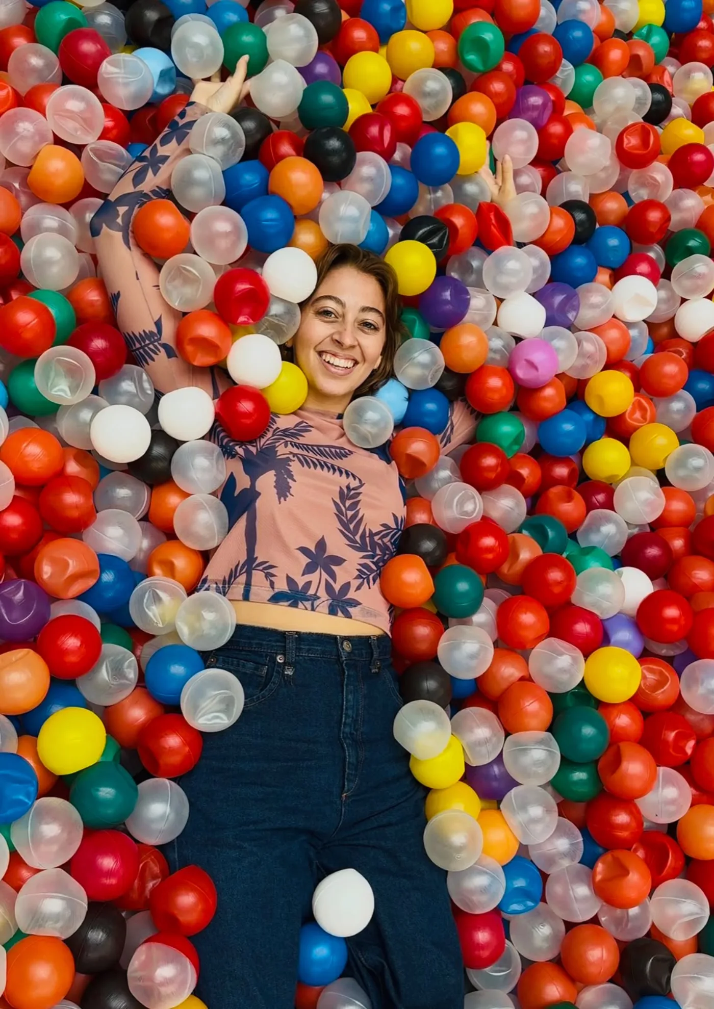 Miriá deitada no meio da piscina de bolinhas, de braços abertos, sorrindo para a câmera.